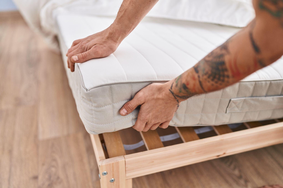 Uomo solleva l'angolo del materasso per mettere il topper letto